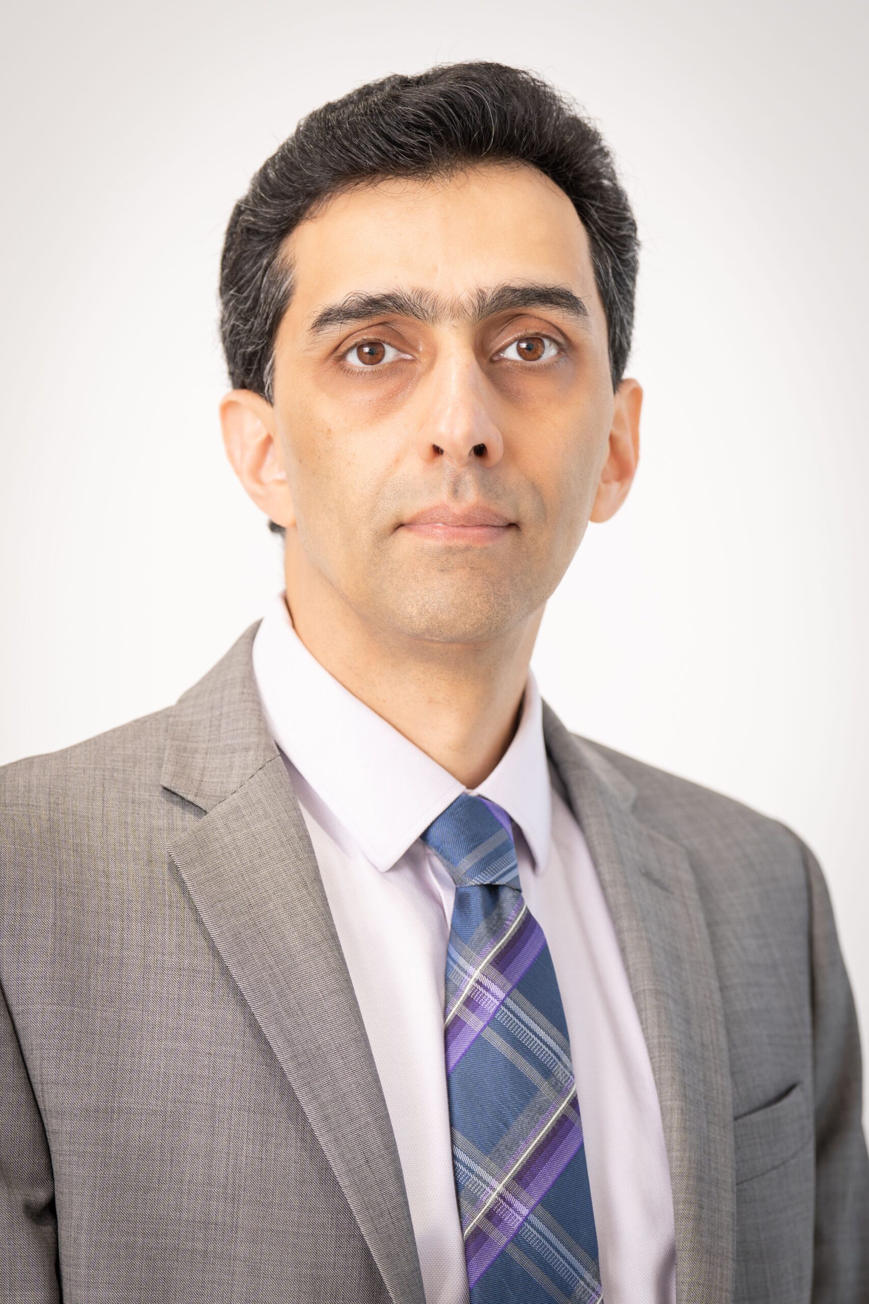 Formal portrait of an adult man wearing a suit and tie, with a white background.